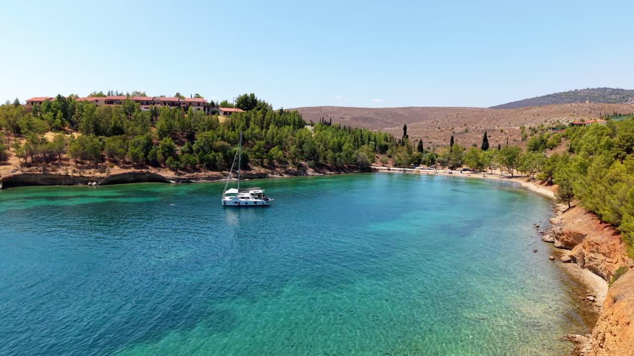 Turquoise waters meet rocky shoreline with pine forest visible along coast near Mornos