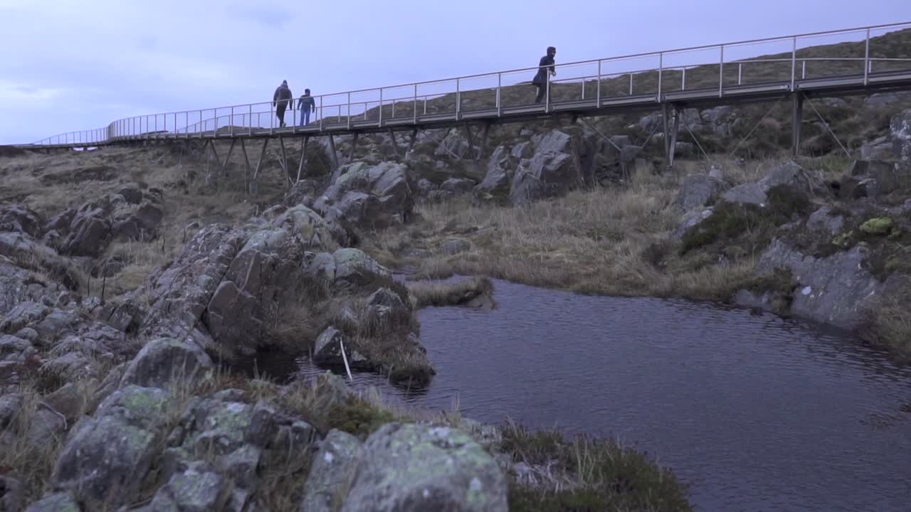 바위 와 물 이 있는 작은 다리 를 가로질러 고 있는 사람 들