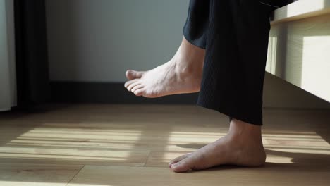 person's bare feet on wooden floor in sunny room