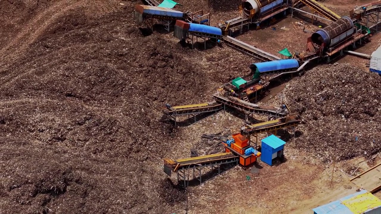 Aerial drone shot showing garbage dump yard with waste piles and conveyor machinery for waste sorting and processing operations at this site in Chennai, Tamil Nadu, India