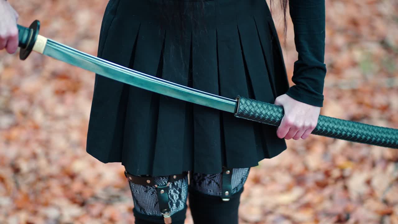 una chica joven con una falda negra con ligas y medias saca una espada katana
