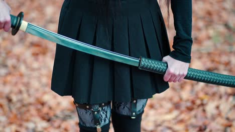 young girl in a black skirt with garters and stockings pulls out a katana sword