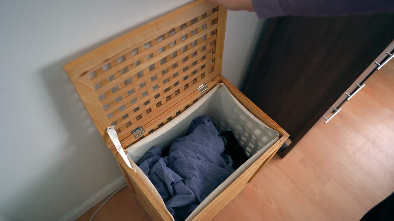 남자는 세탁을 위해 더러운 세탁물을 바구니에 넣는다