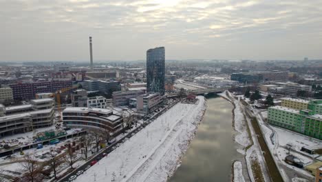 aerial drone shot over snow covered olomouc city in moravia region of czech republic with beautiful modern buildings and bridge over the river passing by on chilly winter evening