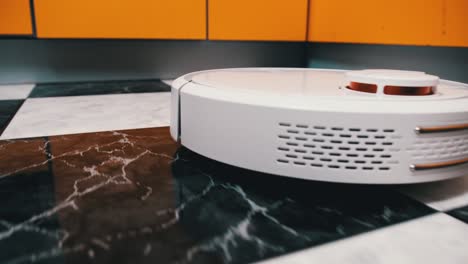 el aspirador robot limpia en la casa moderna en el piso de azulejos en la cocina
