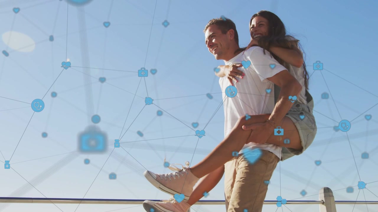 Woman climbing onto man's back, man carrying her on coast for social, icons hovering around couple
