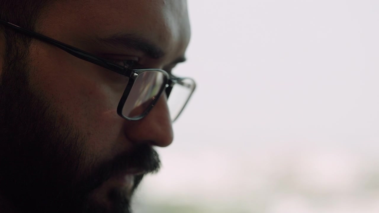 Close-up of a Focused Man Wearing Glasses Working on a Computer