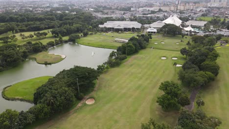 Drone-with-dolly-in-movement-flying-over-golf-course-with-a-lake