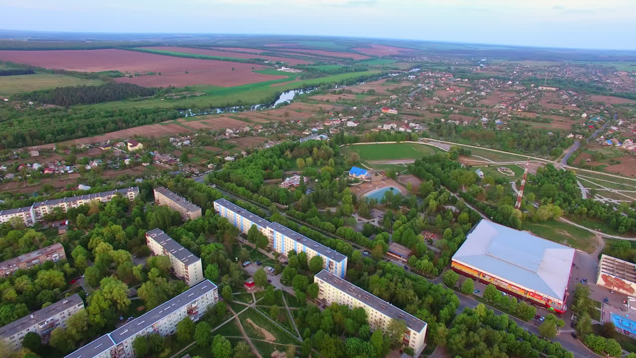 Large green city with multi-storied buildings and little private houses. Green parks and pond in the middle.