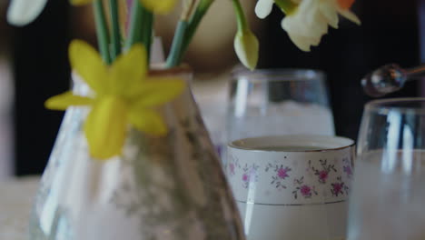 Silver-Tongs-Grasping-a-Sugar-Cube-with-Daffodils-in-the-Foreground