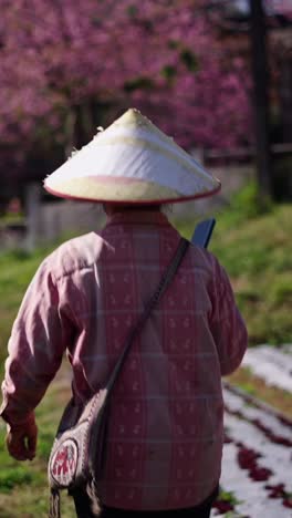 person with asian conical hat in rural field