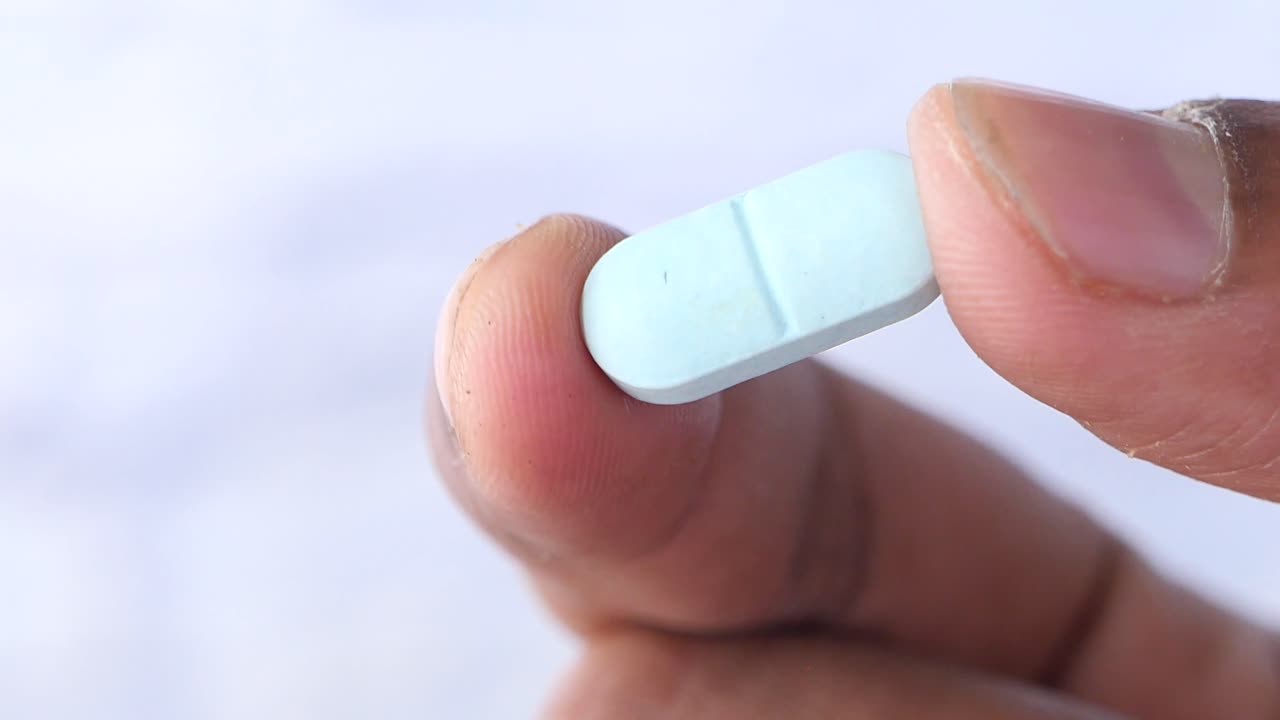 밝은 파란색 약을 들고 있는 손