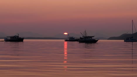 boats on calm ocean water during red smokey sunset