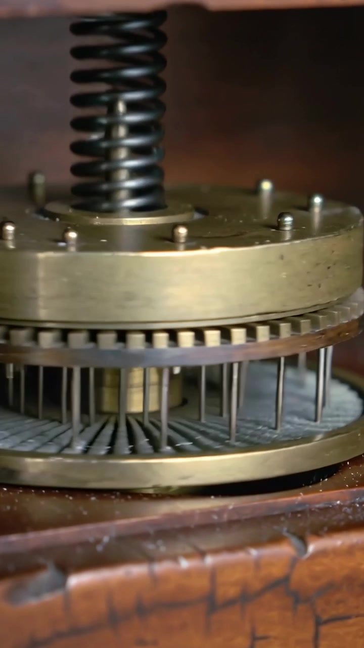 Vertical video: Turning brass music box rotating pinned cylinder plucking comb inside wooden case