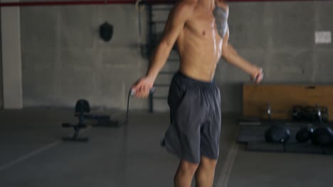 Muscular-man-with-bare-torso-is-jumping-using-a-skipping-rope