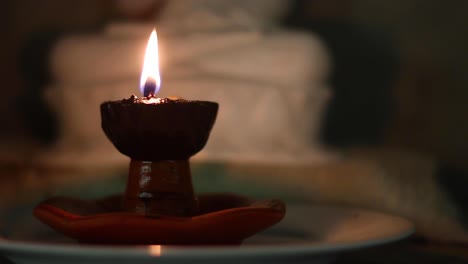 Close-up-static-shot-of-candle-with-flickering-flame-with-Buddha-statue-in-the-back