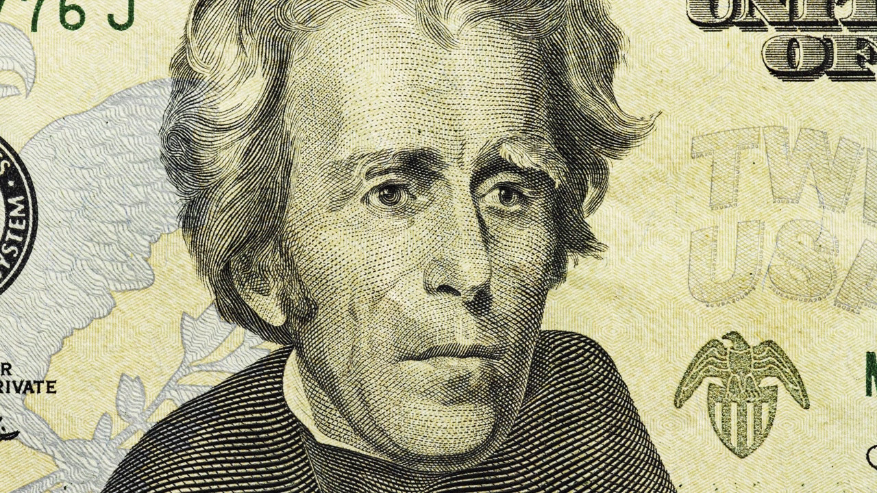 Close pan across U.S. twenty dollar note showing portrait, eagle emblem and text