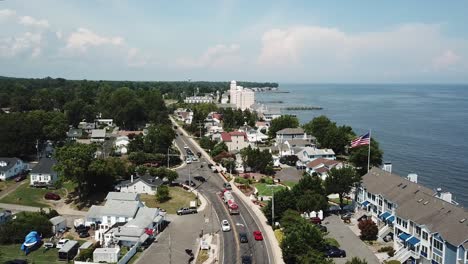 vista aérea de drones sobre el tráfico por carretera y ondeando la bandera americana en la exclusiva zona costera residencial de la bahía de la playa de chesapeake, maryland, ee.uu.