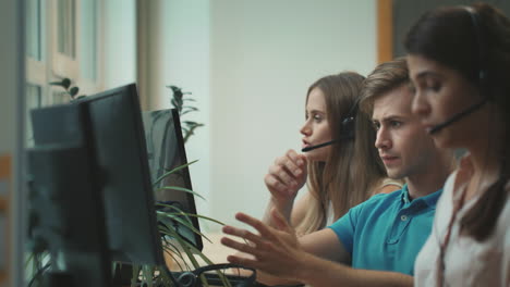 joven lanzando auriculares en el centro de llamadas. trabajador nervioso lanzando equipo