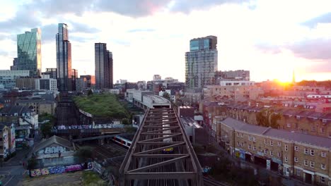 drone shot flying backwards following train on railway in london city