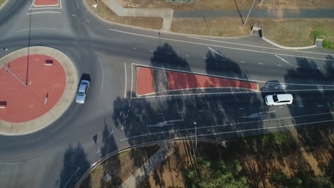 aerial topdown of cars driving through roundabout during morning sunlight in a rural city in australia