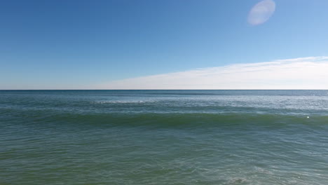 tracking alongside an ocean wave on a calm, blue sky afternoon