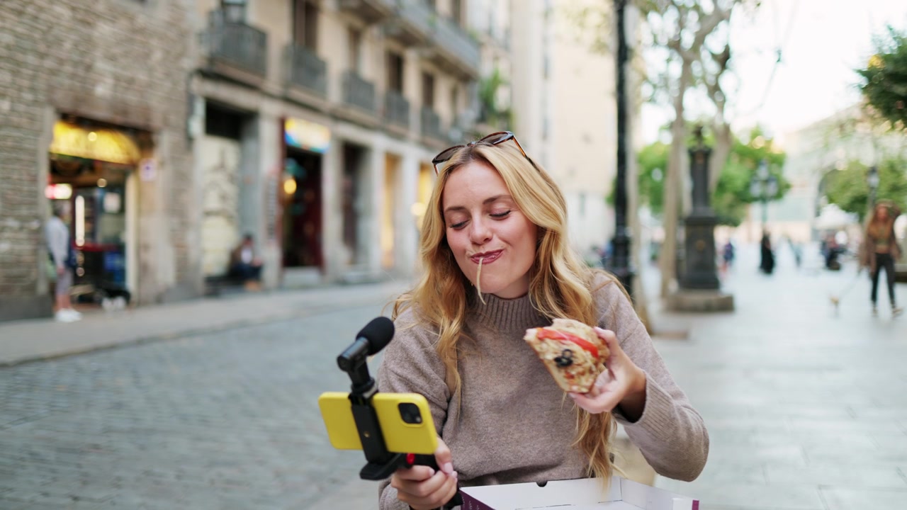 Young Woman Vlogging and Eating Pizza on a City Street