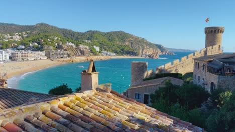 Tossa-de-Mar-bay-seen-from-the-castle-to-the-beach-with-coarse-sand-and-turquoise-blue-sea-water-old-walled-medieval-fishing-village-Mediterranean-sea