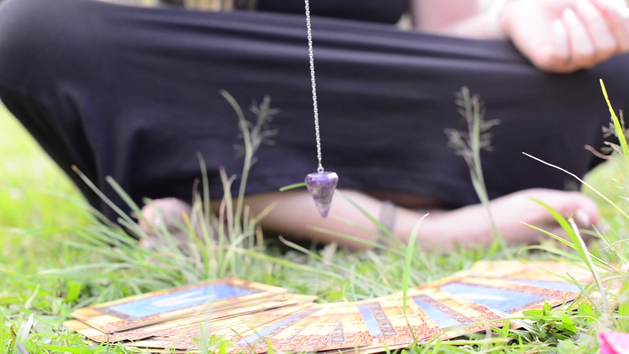 Tangan gadis peramal menggunakan pendulum. Medium spiritual. Ramalan dowsing.