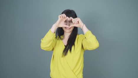 woman making heart sign at camera.