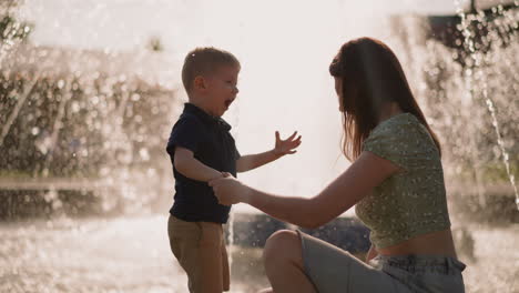 Un-Niño-Emocionado-Juega-Con-Una-Madre-Feliz-Cerca-De-La-Fuente