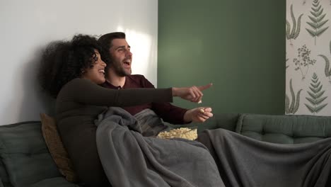 cheerful couple talking while watching tv at home