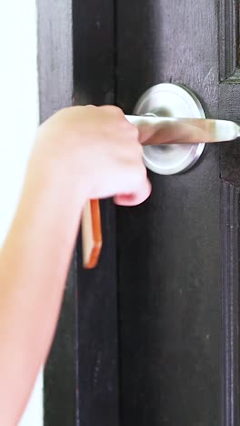 una persona abre una puerta de madera oscura usando una llave, mostrando una acción simple pero enfocada en un entorno brillante