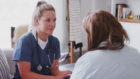 female healthcare worker sitting on sofa with middle aged woman during a home health visit, close up