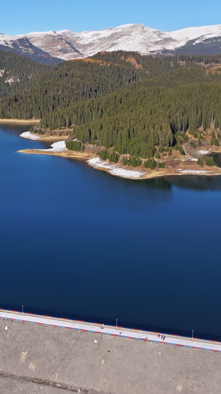 Aerial drone view of the Bolboci Lake in the heart of the mountains, near Brasov, Romania. Vertical