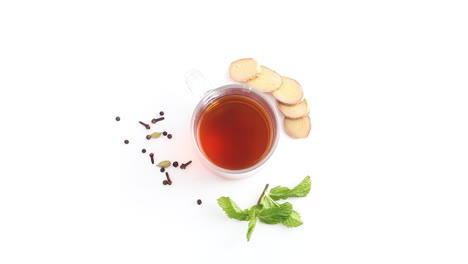 té de limón en una taza de vidrio transparente con limón entero y en rodajas en un plano superior giratorio de fondo blanco