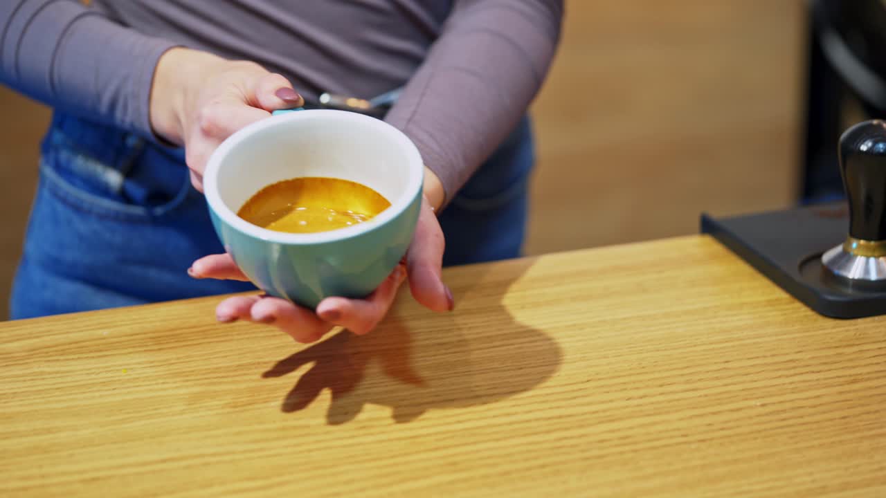 Making fresh coffee. Process of making espresso in a coffee machine. Woman takes the cup of hot coffee and shows it to camera.