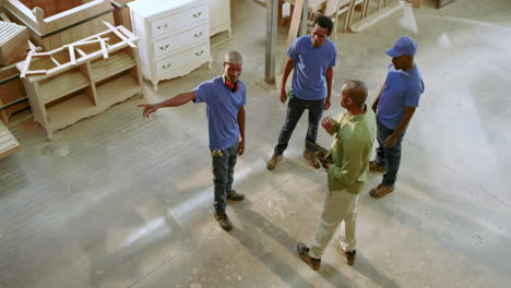 african american man leading workers as unfolding clipboard plan and assigning tasks in workshop