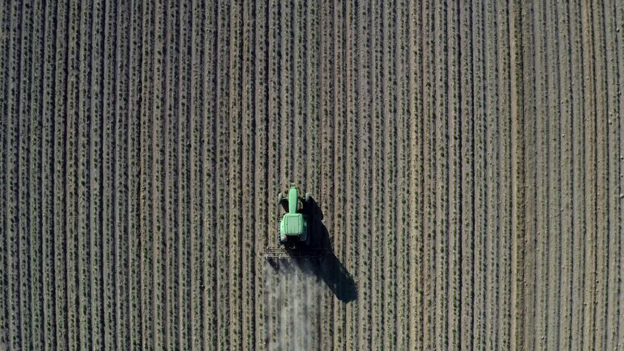 A Tractor Plowing The Farm Field On A Bright Sunny Day - Dusty Drought Life -  Aerial Shot