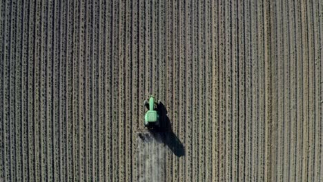 a tractor plowing the farm field on a bright sunny day - dusty drought life -  aerial shot