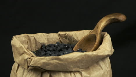 narrow depth of field: dry black beans rotate in paper bag, dark room