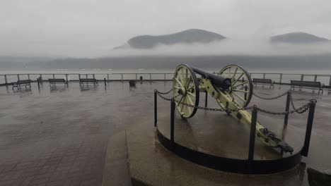 historical-cannon-and-homes-on-the-Cold-Spring,-New-York-waterfront,-on-a-rainy,-foggy,-beautiful-atmospheric-day-day