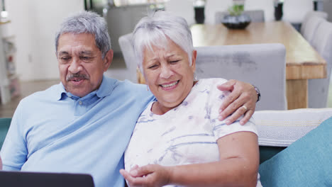 Happy-senior-biracial-couple-waving-and-having-video-call