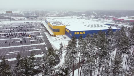 perspectiva aérea del minorista de muebles más grande del mundo, ikea, que vende muebles listos para ensamblar, con un edificio de varias cadenas cubierto de nieve con un gran espacio de estacionamiento en la calle en riga, letonia