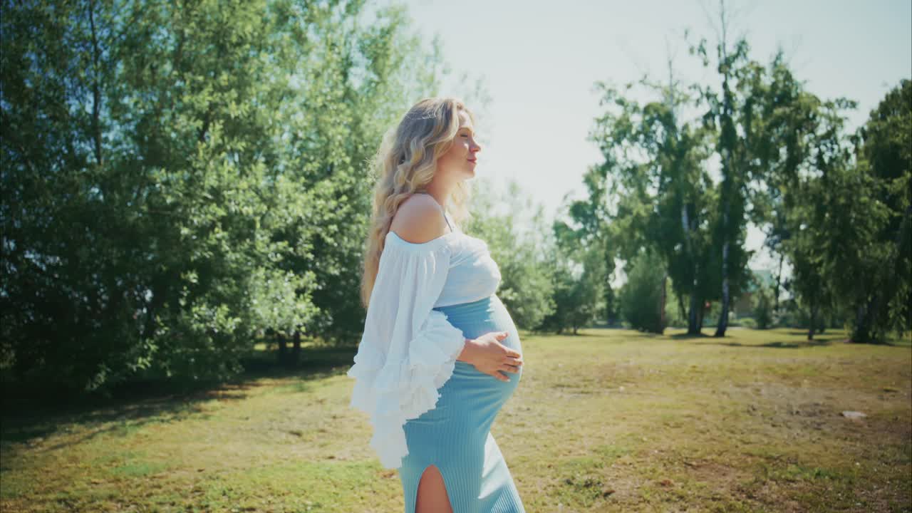 Happy Pregnant Woman Walking in a Sunny Park