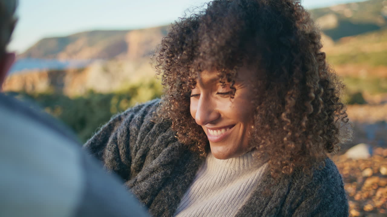 Relaxed brunette lying cliff nature smiling closeup. Happy curly woman flirting