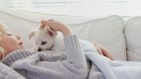 Little-girl-lying-on-sofa-stroking-her-pet-at-home-4K-4k