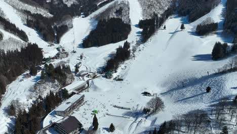 push in, pan down shot of bottom of ski run, skiers arriving at base of mountain lining up for the chairlifts