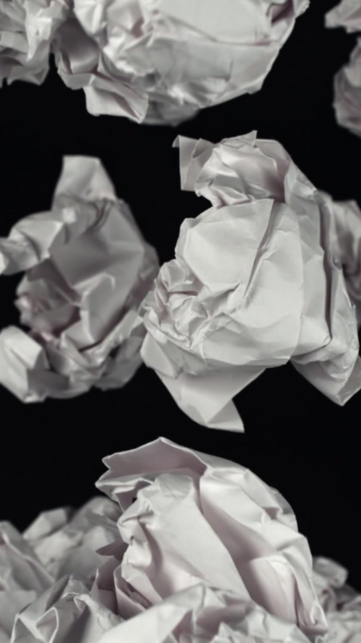 Slow Motion of Crumpled White Paper Falling on Black Background