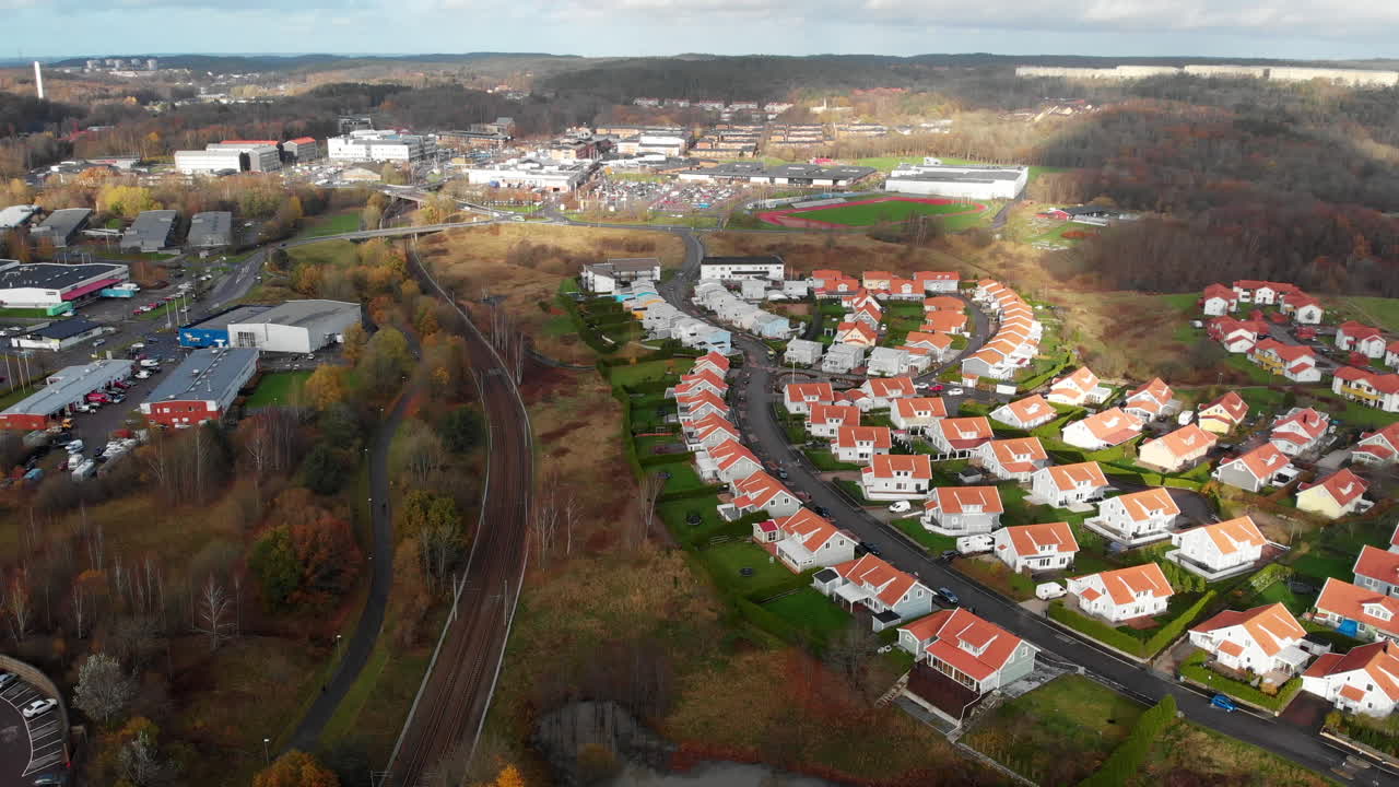 Svenske forstads ejendomme ved jernbanen, luftdrone flyver fremad på en skyet dag